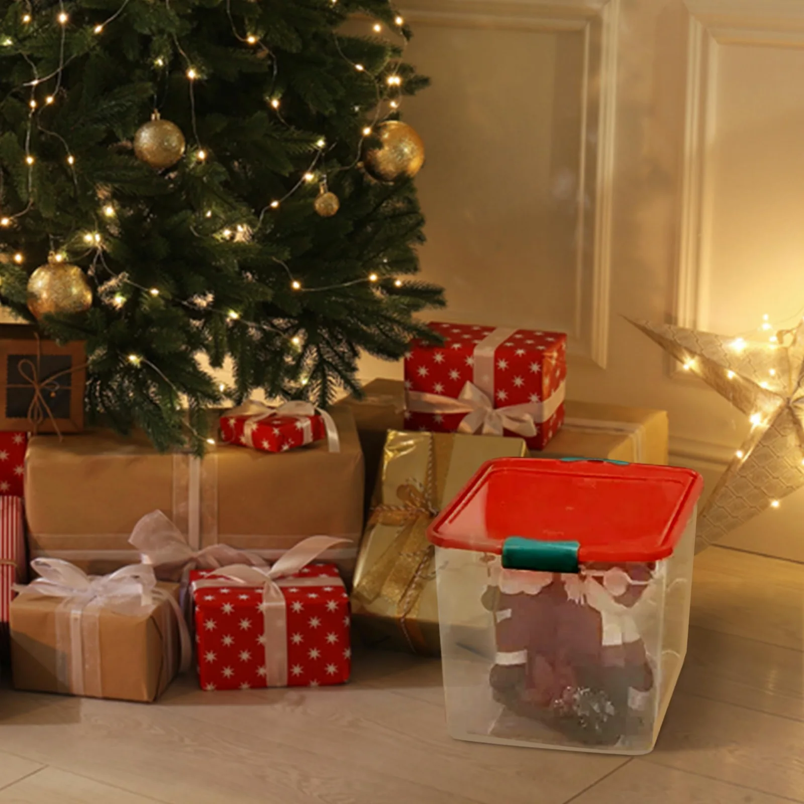 A HOMZ clear holiday tote with a red lid beside a decorated tree and wrapped gifts